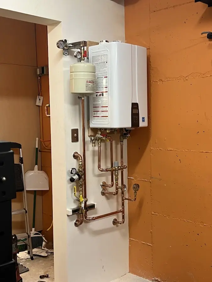Plumbing technician inspecting water heater connections in Erie